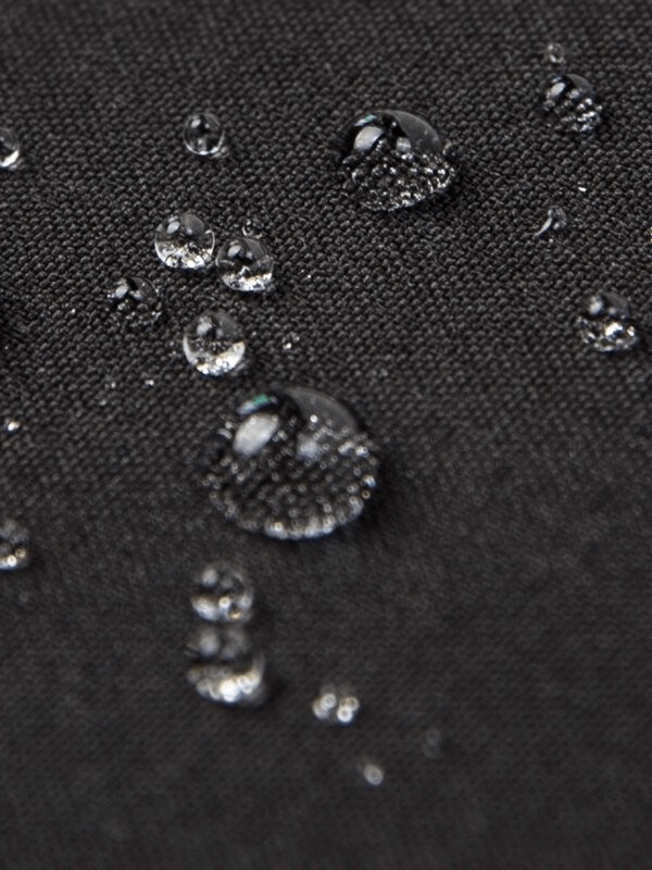 Close-up of water droplets on women's windproof waterproof fleece pants fabric, showcasing water-resistant material.
